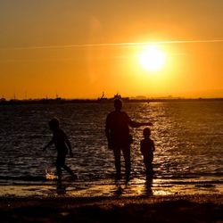 Silhouette of people on beach at sunset
