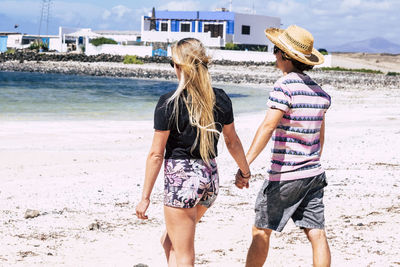 Man and woman walking towards sea at beach