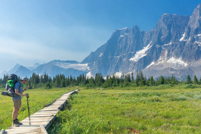 Rear view of man walking on mountain against clear sky