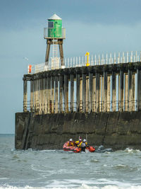 People on lifeboat in sea by pier