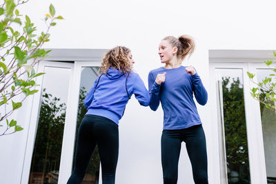 Low angle view of women standing by window outdoors