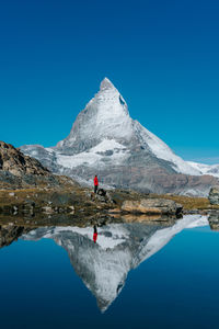 Rear view of man on lake against clear blue sky