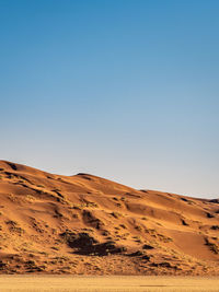 Scenic view of desert against clear blue sky
