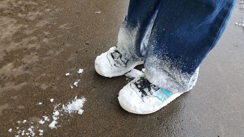 Low section of man wearing frozen shoes standing on road