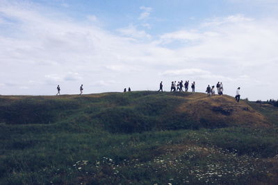 People walking on hill against sky