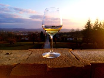 Glass of wine on table against sky during sunset