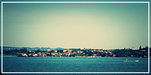 Scenic view of river by city against clear sky