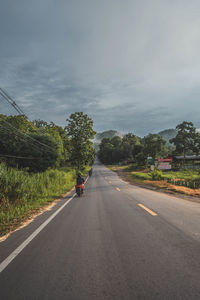 Person riding motorcycle on road against sky