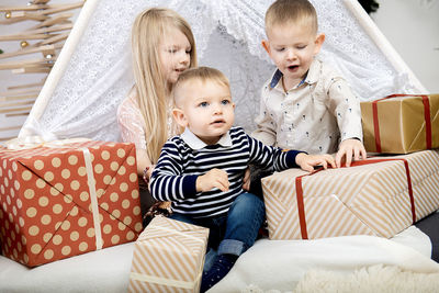 Three children kids sitting between christmas gift boxes in a decorated house.merry christmas 