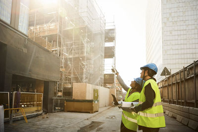 Female engineers in reflective clothing discussing at construction site