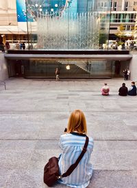 Rear view of two people sitting in city