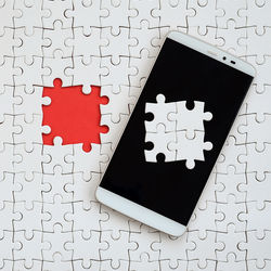 High angle view of smart phone against jigsaw puzzle 