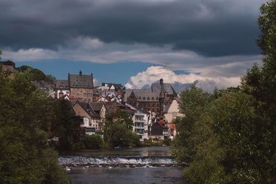 Buildings by river against sky