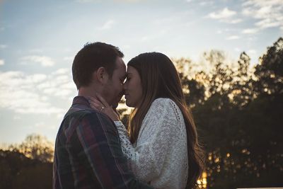 Portrait of couple kissing against sky at night