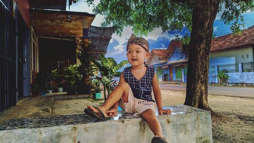 Portrait of young man sitting against old abandoned house