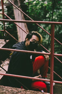 Portrait of man wearing mask while sitting on steps