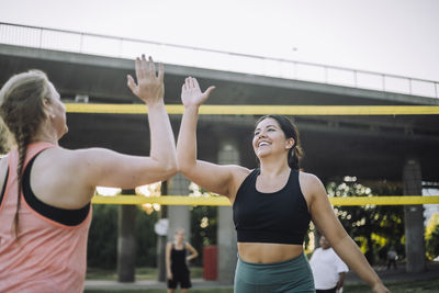 Happy female friend giving high-five during volleyball match