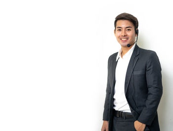 Portrait of young man standing against white background