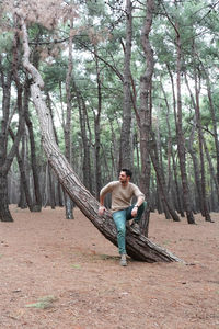 Man sitting on tree trunk at forest