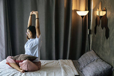 Young woman sitting on bed at home