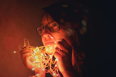 Close-up of young woman holding illuminated lighting equipment