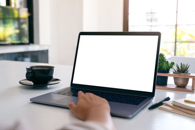 Coffee cup and laptop on table