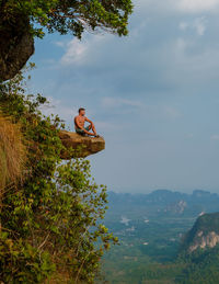 Low angle view of man sitting on mountain