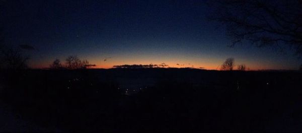 Silhouette of trees on landscape at sunset