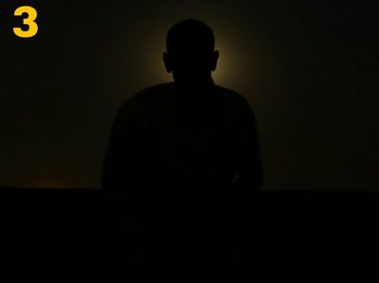Silhouette man standing in illuminated darkroom