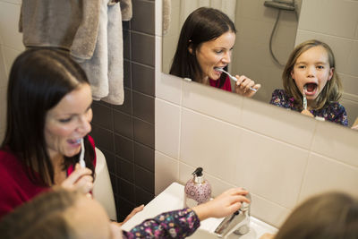 Mother and daughter brushing teeth in bathroom