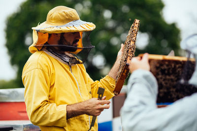 Rear view of man holding yellow while standing outdoors