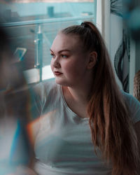 Young woman looking though window