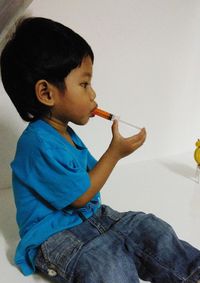 Side view of boy eating man sitting