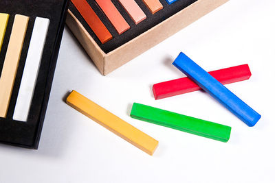 High angle view of multi colored crayons against white background