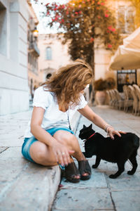 Rear view of woman with dog sitting outdoors