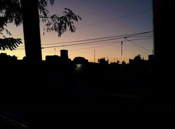 Silhouette built structures against sky at sunset