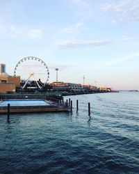 Ferris wheel by sea against sky