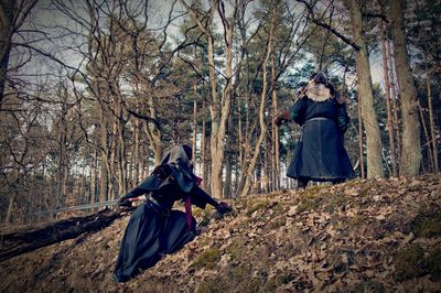 Women wearing stage costumes standing amidst trees in forest