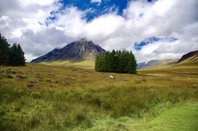 Scenic view of green landscape and mountains against sky