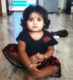 Portrait of cute girl sitting on floor at home