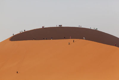 People on desert against clear sky