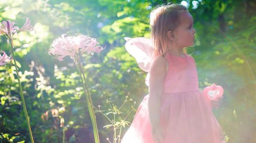 Girl in fairy costume against trees on sunny day