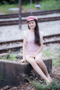 Portrait of woman sitting against railroad track