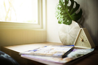 Close-up of magazines and alarm clock on table at home