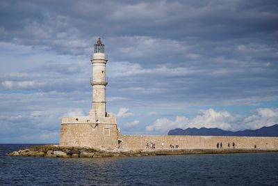 Lighthouse by sea against sky