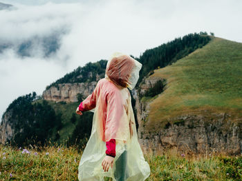 Rear view of woman standing on field against sky