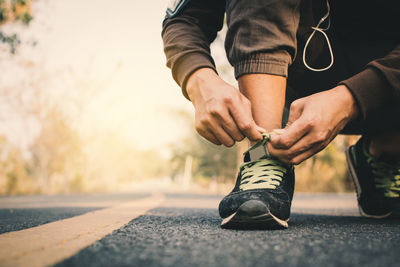 Low section of man tying shoelace on road