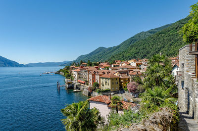 Scenic view of sea by buildings against clear blue sky