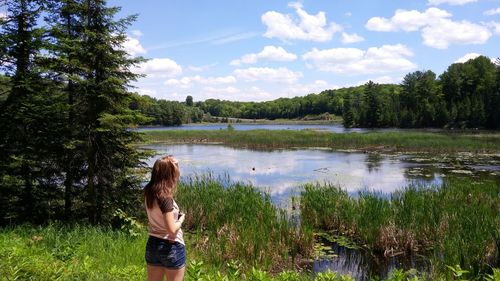 Rear view of man standing by lake against sky