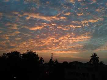 Low angle view of silhouette trees against cloudy sky